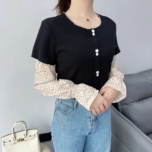 Detail of floral chiffon sleeves on a black knit top with decorative flower buttons