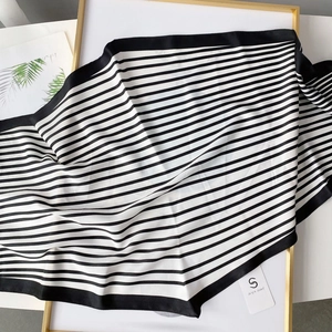 Detail of elegant black and white striped silk scarf with premium hem on a display stand