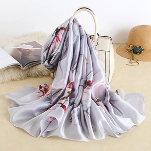 Close-up of elegant floral silk scarf draped over a handbag with a soft glossy texture