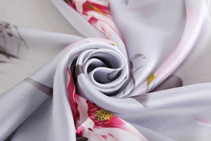 Macro shot showing soft silk texture and elegant floral pattern on grey silk scarf