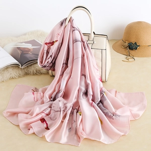 Elegant pink silk scarf with floral print draped over a stylish white handbag