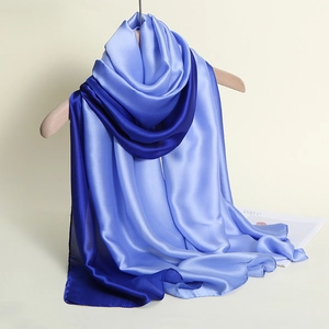 Close-up of elegant gradient blue silk satin scarf hanging on a wooden hanger