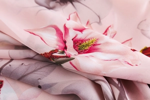 Macro shot of elegant magnolia pattern on soft pink faux silk scarf fabric