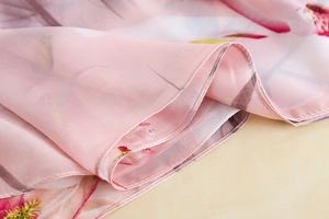 Detail of pink floral silk scarf showing delicate edge stitching and chiffon texture