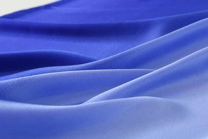 Macro detail of blue gradient silk scarf fabric showing smooth color transition and texture
