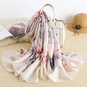 Detailed texture of elegant floral silk scarf draped over a stylish cream handbag