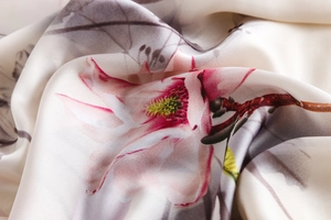 Close-up of silk scarf fabric showing elegant pink floral patterns and delicate texture