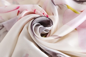 Macro detail showing smooth satin texture and elegant floral print on silk scarf fabric