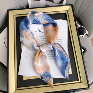 Close-up of silk feel scarf with blue and orange tie-dye patterns in a gold frame