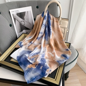 Artistic tie-dye silk-feel scarf draped over a handbag in a stylish interior setting