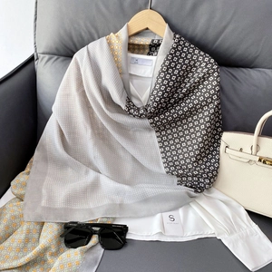 Détail d'un foulard en soie à pois gris et motifs géométriques sur une chemise blanche