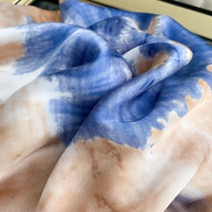 Macro detail of silk texture with tie-dye watercolor print in blue and beige