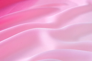 Macro shot of gradient pink silk fabric showing soft wavy pleats and smooth texture