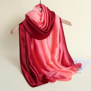 Detail of gradient pink to red silk satin scarf hanging naturally on a wooden hanger