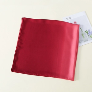 Detailed view of dark red satin silk scarf texture with a floral magazine on the side