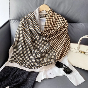Vue détaillée d'une écharpe en soie avec motif à pois rétro sur fond de cuir gris