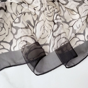 Close-up detail of camellia silk scarf with monochrome rose patterns and sheer black borders