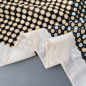 Détail macro d'une écharpe en coton et lin avec motifs géométriques et bords roulés fins