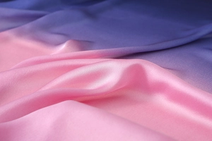 Macro detail of high-quality silk scarf fabric with pink to purple gradient and satin texture