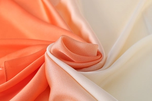 Macro shot of silk scarf showing smooth gradient texture from warm orange to light beige