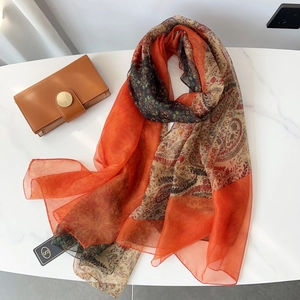 Detail of bohemian orange paisley scarf texture on a white marble background