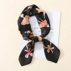Détail d'un foulard en satin aux motifs de ballerine noué en nœud sur fond beige chic
