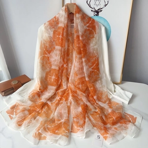 Écharpe légère à fleurs orange et blanches drapée élégamment sur une chemise blanche