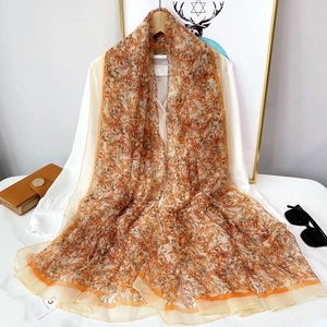Détail du châle en mousseline à imprimé floral orange et marron, texture légère
