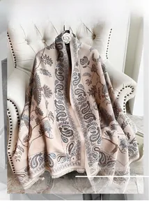 Dettaglio di scialle invernale in cashmere con motivo paisley e nappe su poltrona