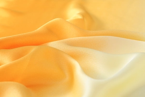 Macro view showing the smooth texture and gradient yellow silk satin fabric transition
