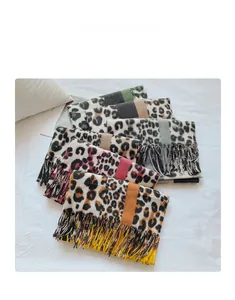 Detail view showing four leopard print scarves with long fringe tassels in various colors