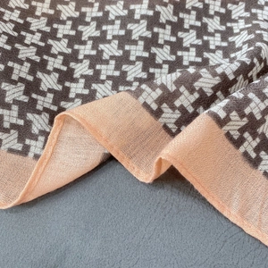 Close-up of houndstooth plaid scarf texture with orange stitched edge detail