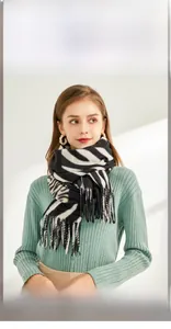 Détail d'une écharpe à motif zèbre avec franges sur un pull vert pour un look d'hiver