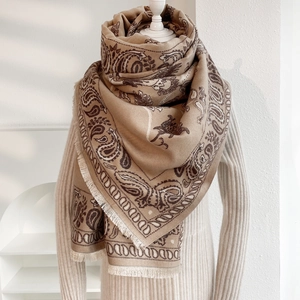 Dettaglio della sciarpa in cashmere con motivo paisley color cammello e nappe eleganti