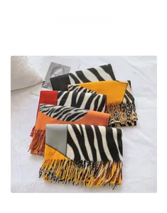 Close-up of zebra pattern knitted scarves with tassels in mustard and orange shades