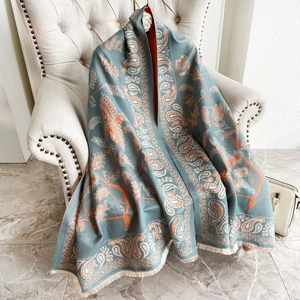 Sciarpa in cashmere blu con motivi paisley e uccelli e nappe su un divano