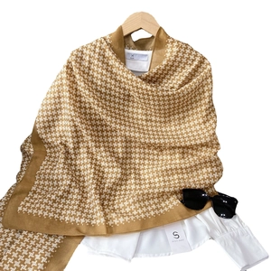 Classic brown houndstooth scarf displayed on a wooden hanger with modern fashion accessories