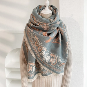 Dettaglio della sciarpa in cashmere paisley con frange nei toni grigio-blu e arancio