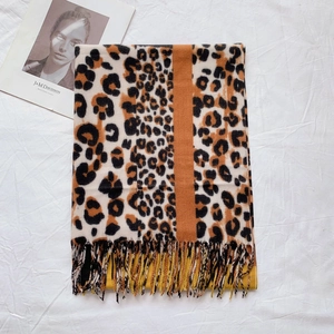 Detail showing soft leopard print scarf texture with orange stripe and fine tassels