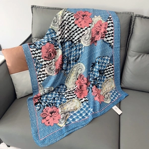 Lightweight blue floral scarf with pink blossoms and paisley patterns on a grey sofa