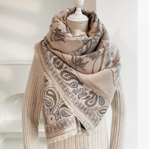 Dettaglio di sciarpa beige con motivo paisley e frange corte su manichino