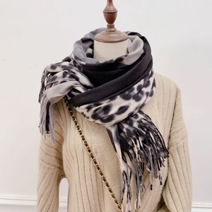 Detail of grey leopard print scarf with long tassels on beige knit sweater