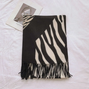Detailed macro view of zebra pattern scarf with dense black tassel fringes on white fabric
