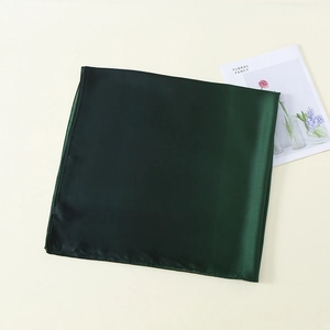 Close-up of a dark green satin silk scarf with elegant sheen and premium texture
