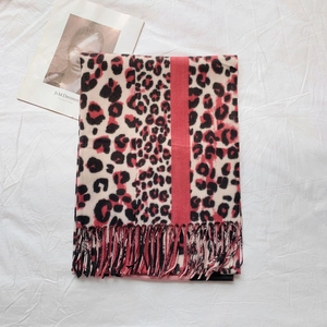 Detail of leopard print scarf with red stripe and soft pink fringe on white fabric