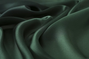 Macro shot of dark green satin silk scarf showing smooth texture and elegant drape