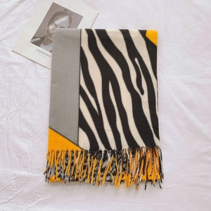 Détail de l'écharpe imprimé zèbre avec pompons, blocs de couleur orange et gris