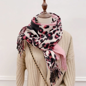 Close-up of pink leopard print scarf with long fringe details on beige cardigan
