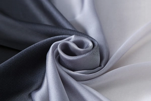 Macro shot of gradient grey silk satin fabric twisted into a rose shape detail