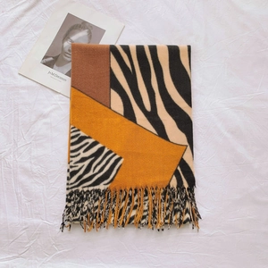 Detail of zebra pattern scarf with tassels and geometric color blocks in brown and yellow